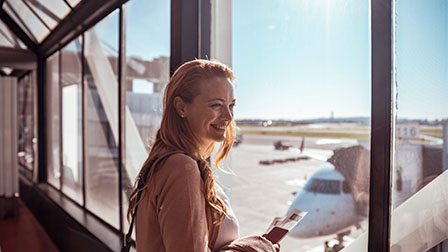Tu viaje paso a paso Woman at the airport looking out of the window at the plane she will be travelling on