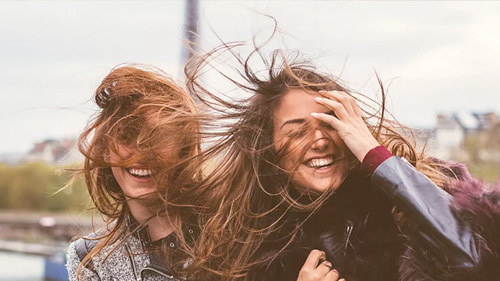 Iberia Joven Two young women laughing as the wind blows their hair