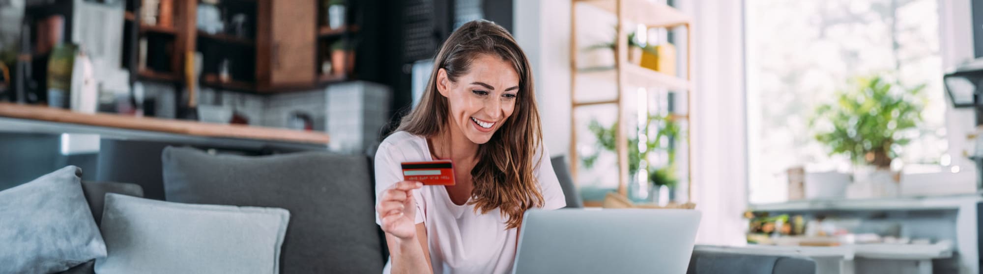 The image shows a woman smiling while holding a credit card